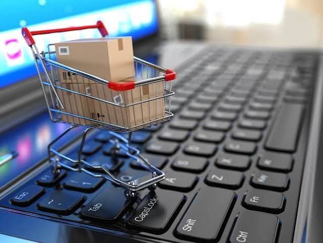 Miniature shopping cart with cardboard parcels sitting on a laptop keyboard, representing ecommerce bookkeeping for Shopify stores